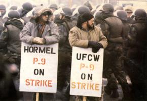 P-9 strikers on the picket line, surrounded by riot-clad National Guard troops