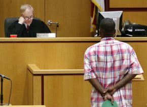 A Black defendant faces a judge in a U.S. courtroom